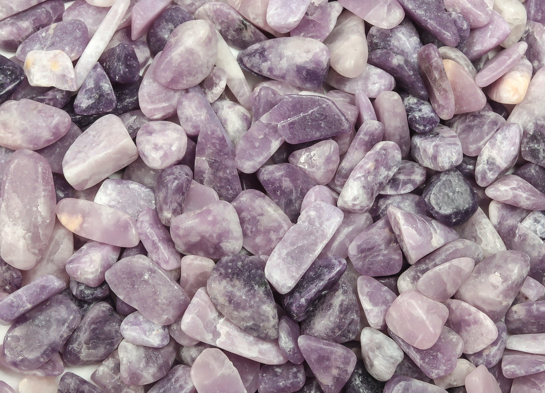 Lepidolite crystal chips in bulk, semi-tumbled 7-12mm gemstones from GemstoneGO showing purple and pink hues in a close-up image.