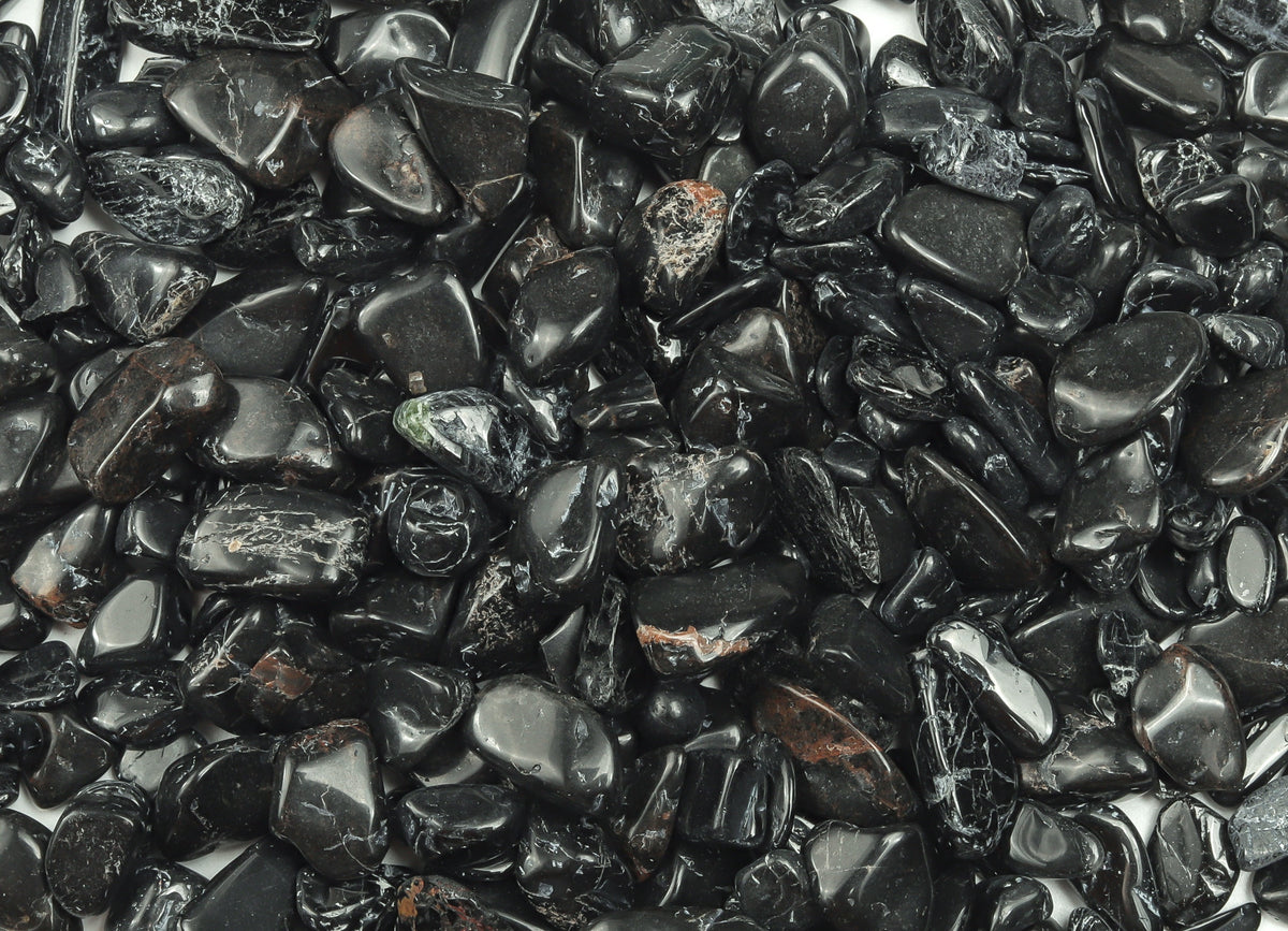 Black tourmaline crystal chips in semi-tumbled 7-12mm size, shown in bulk with irregular black stone pieces from GemstoneGO