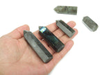 Labradorite obelisk tower crystal from GemstoneGO showcasing iridescent stone with natural mineral patterns and a pointed top.