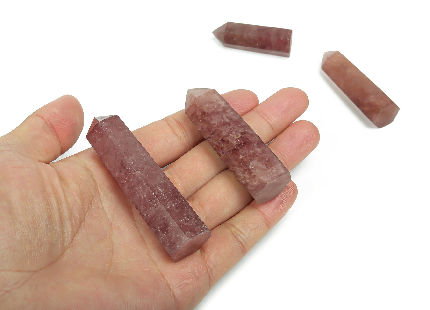 Strawberry Quartz obelisk tower crystal from GemstoneGO, showcasing a pink, polished gemstone with natural striations and a pointed tip.
