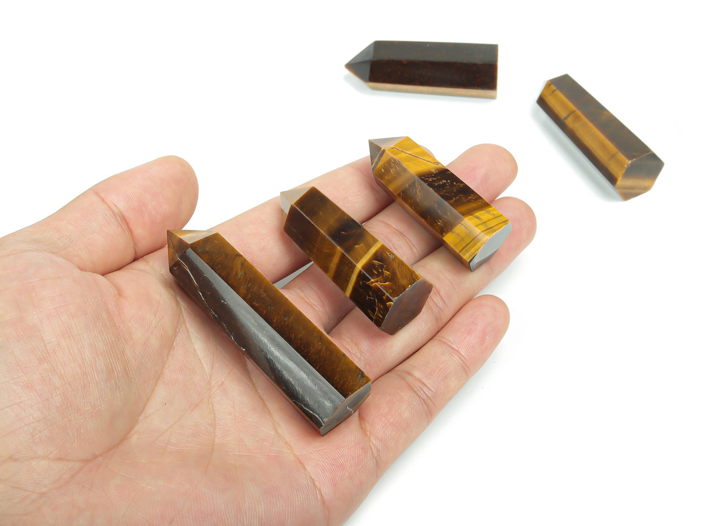 Tiger Eye obelisk tower crystal from GemstoneGO, featuring a polished golden-brown stone with natural banding and a pointed top.