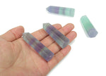 Polished fluorite obelisk tower crystal from GemstoneGO with vibrant purple and green hues, showcasing a smooth, pointed design.