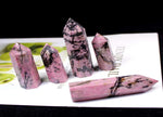 Rhodonite obelisk tower crystal from GemstoneGO, featuring pink and black stone with polished, pointed shape and natural mineral textures.