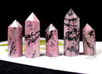 Rhodonite obelisk tower crystal from GemstoneGO showing a pink and black mineral stone with natural striations and polished surface.