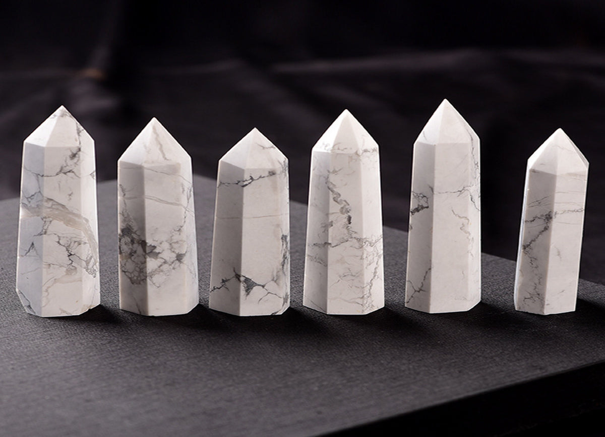 Howlite obelisk tower crystal from GemstoneGO, showcasing a smooth white stone with gray veining on a clear base.