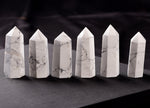 Howlite obelisk tower crystal from GemstoneGO, showcasing a smooth white stone with gray veining on a clear base.