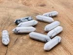 Howlite terminated carved point gemstone, 33mm, from GemstoneGO, showing smooth white stone with gray veining and pointed tip.