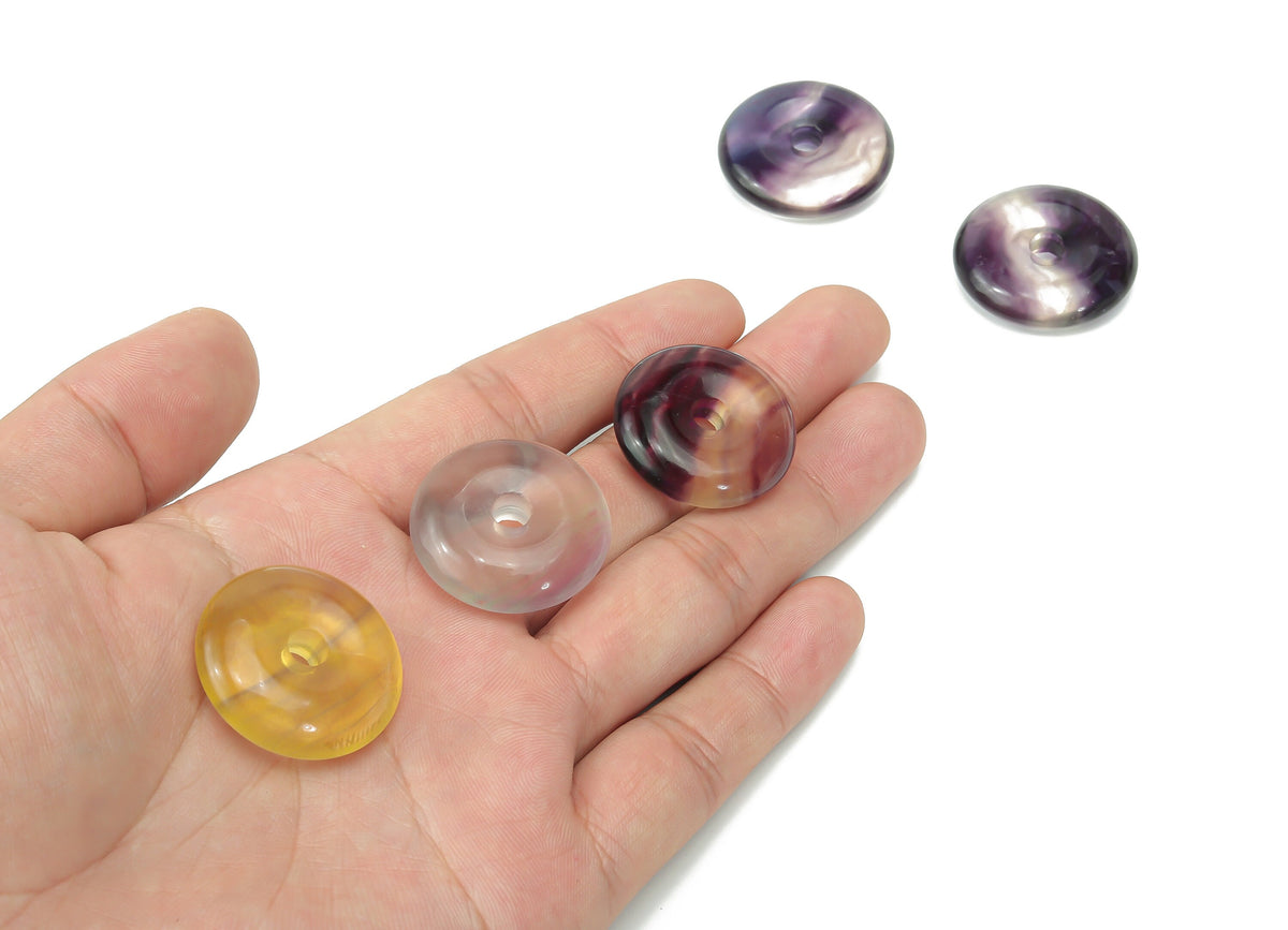 Polished fluorite crystal donut from GemstoneGO, 30mm Pi stone with vibrant green and purple hues, smooth, rounded gemstone.