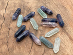 A 33mm fluorite terminated carved point gemstone from GemstoneGO, displaying vibrant purple and green hues with natural banding.