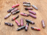 Rhodonite terminated carved crystal point, 33mm, from GemstoneGO featuring pink and black layered mineral pattern.