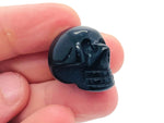 Carved 25mm obsidian gemstone skull with detailed features, showcasing a smooth, polished black stone design.