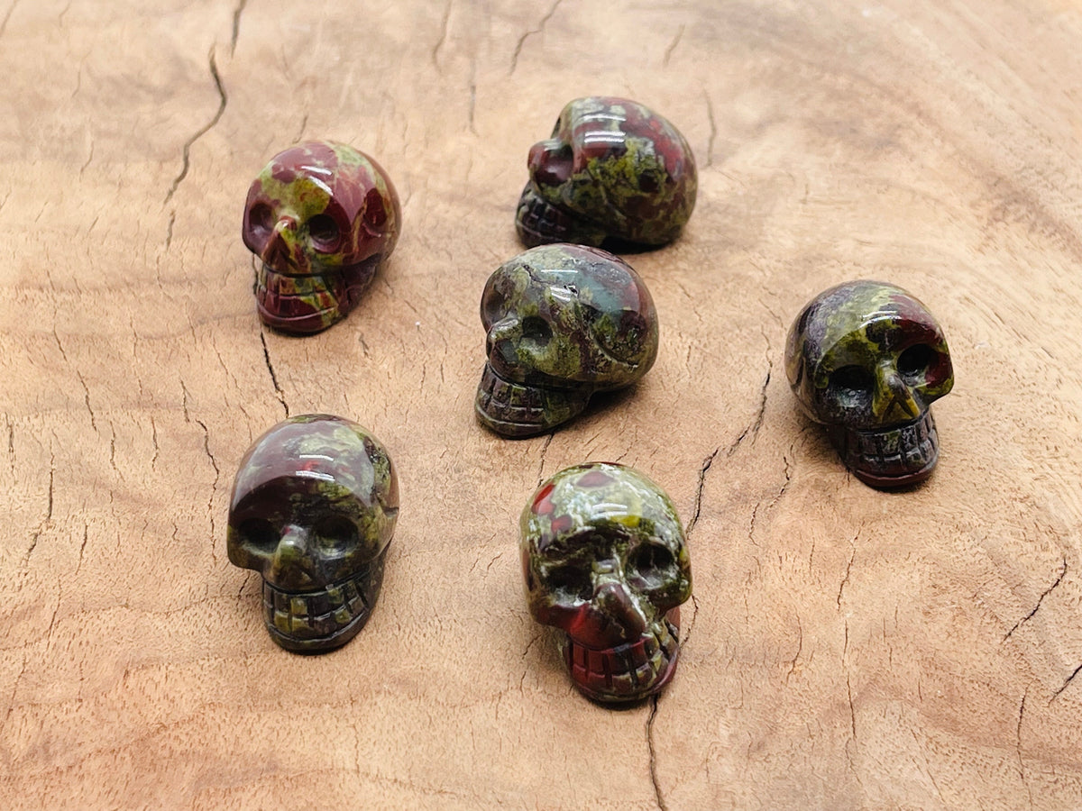 Carved Dragon Blood Jasper skull gemstone, 25mm, showing detailed red and brown natural stone patterns and smooth polished surface.