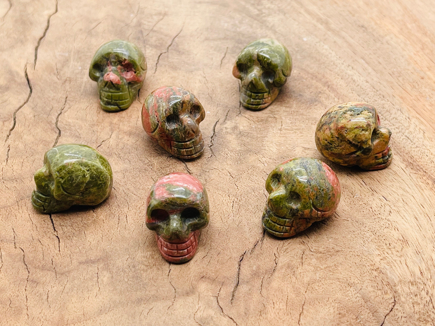 Unakite skull carved gemstone, 25mm, showing detailed green and pink mineral patterns on a polished surface.