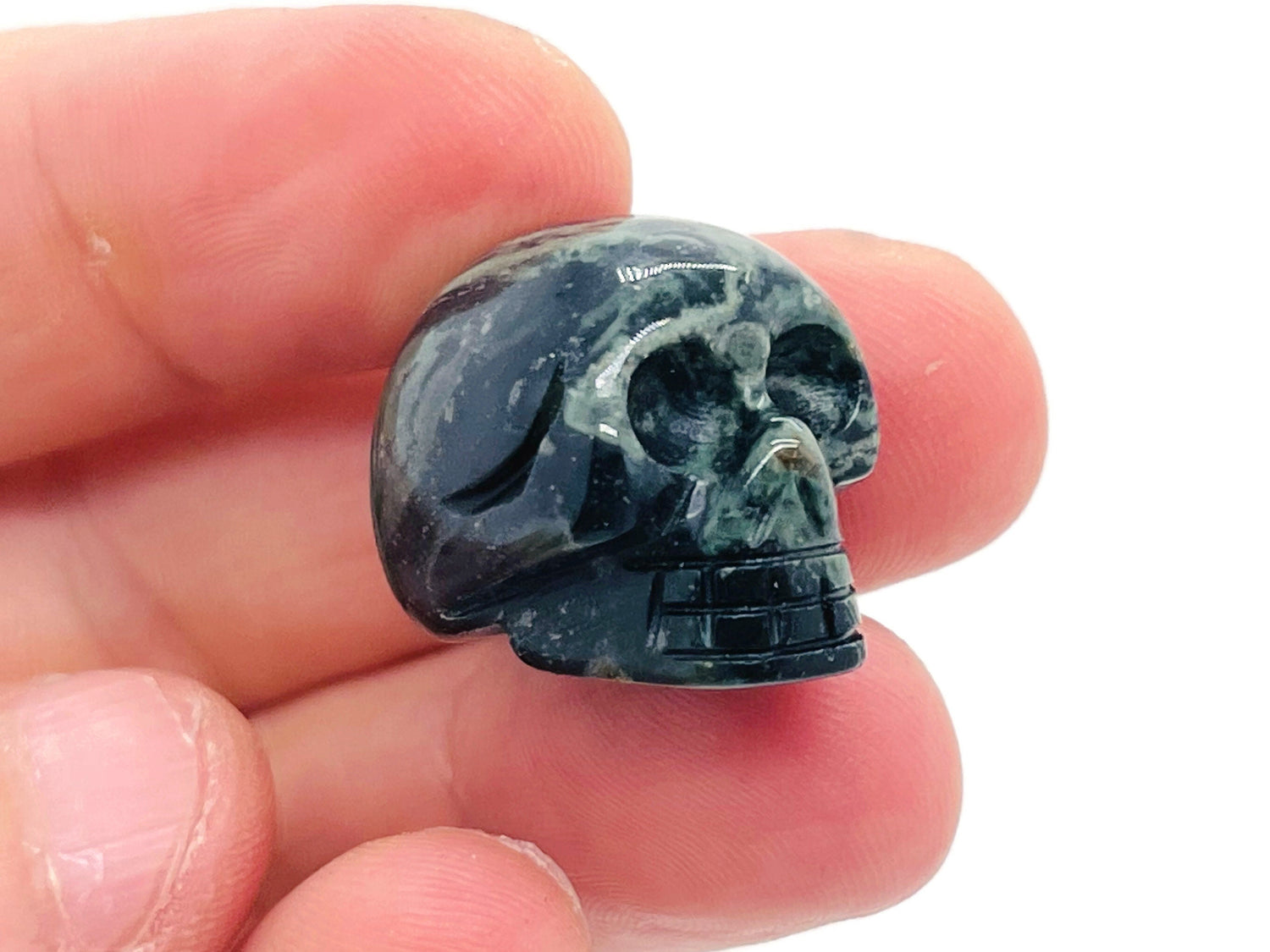 Kambaba Jasper skull carved gemstone, 25mm, featuring swirling green and black patterns, polished and detailed for display or collection.