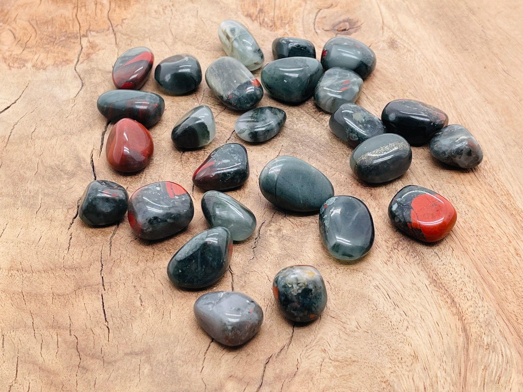 African Bloodstone tumbled stone from GemstoneGO, showcasing deep green and red mineral patterns with a smooth polished surface.