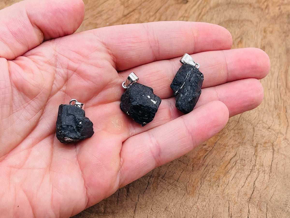 Black Tourmaline crystal pendant by GemstoneGO featuring a polished black gemstone with a silver bail on a chain.