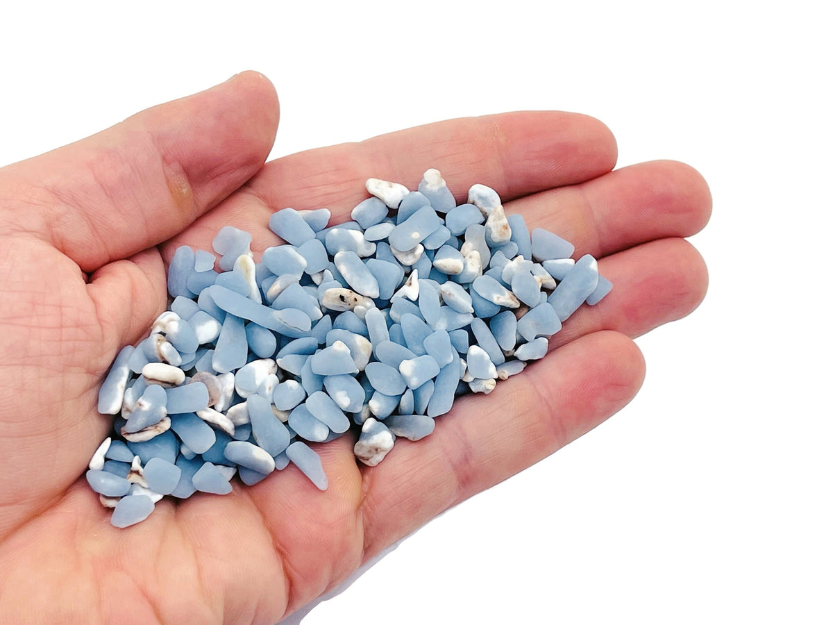 Semi-tumbled Angelite crystal chips in 5-7mm, displayed in bulk from GemstoneGO, showcasing smooth, pale blue gemstone fragments.