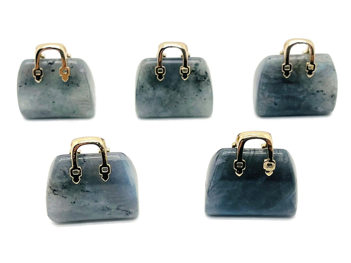 Labradorite crystal handbag pendant carving, gemstone jewelry accessory with intricate purse design on a polished stone.