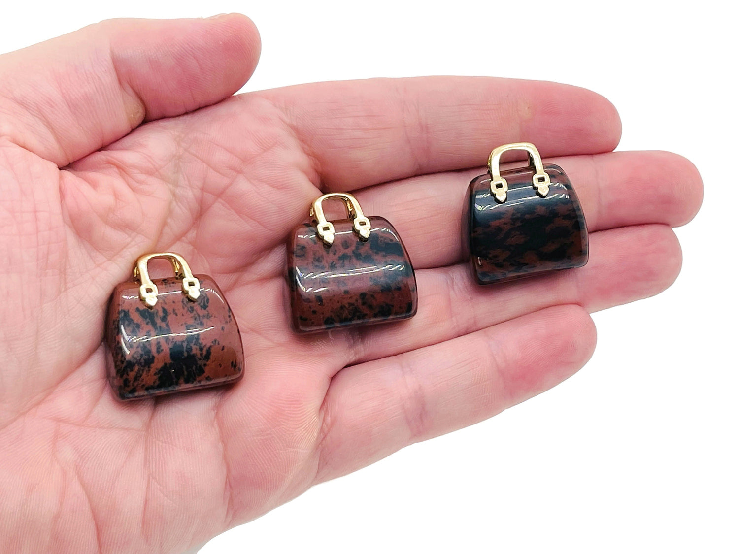 Mahogany Obsidian crystal purse carving gemstone pendant with intricate hand-carved design, hanging from a metal chain.