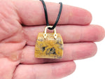 Crazy Lace Agate crystal carved as a purse-shaped gemstone pendant with intricate patterns, designed as a stylish handbag accessory.