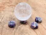 Amethyst crystal sphere on a carved gemstone stand, used as elegant home decor with vibrant purple hues.