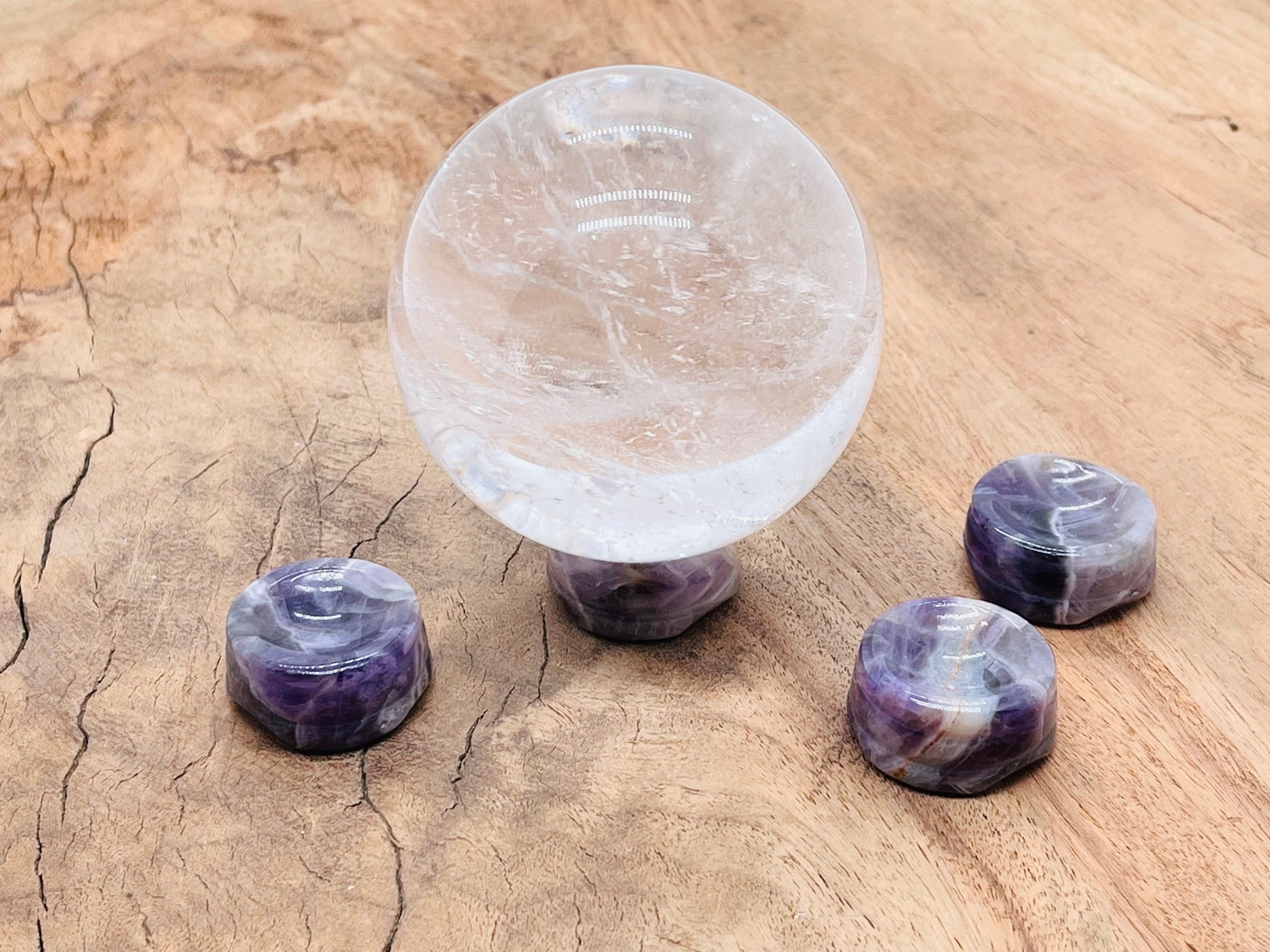 Amethyst crystal sphere on a carved gemstone stand, used as elegant home decor with vibrant purple hues.