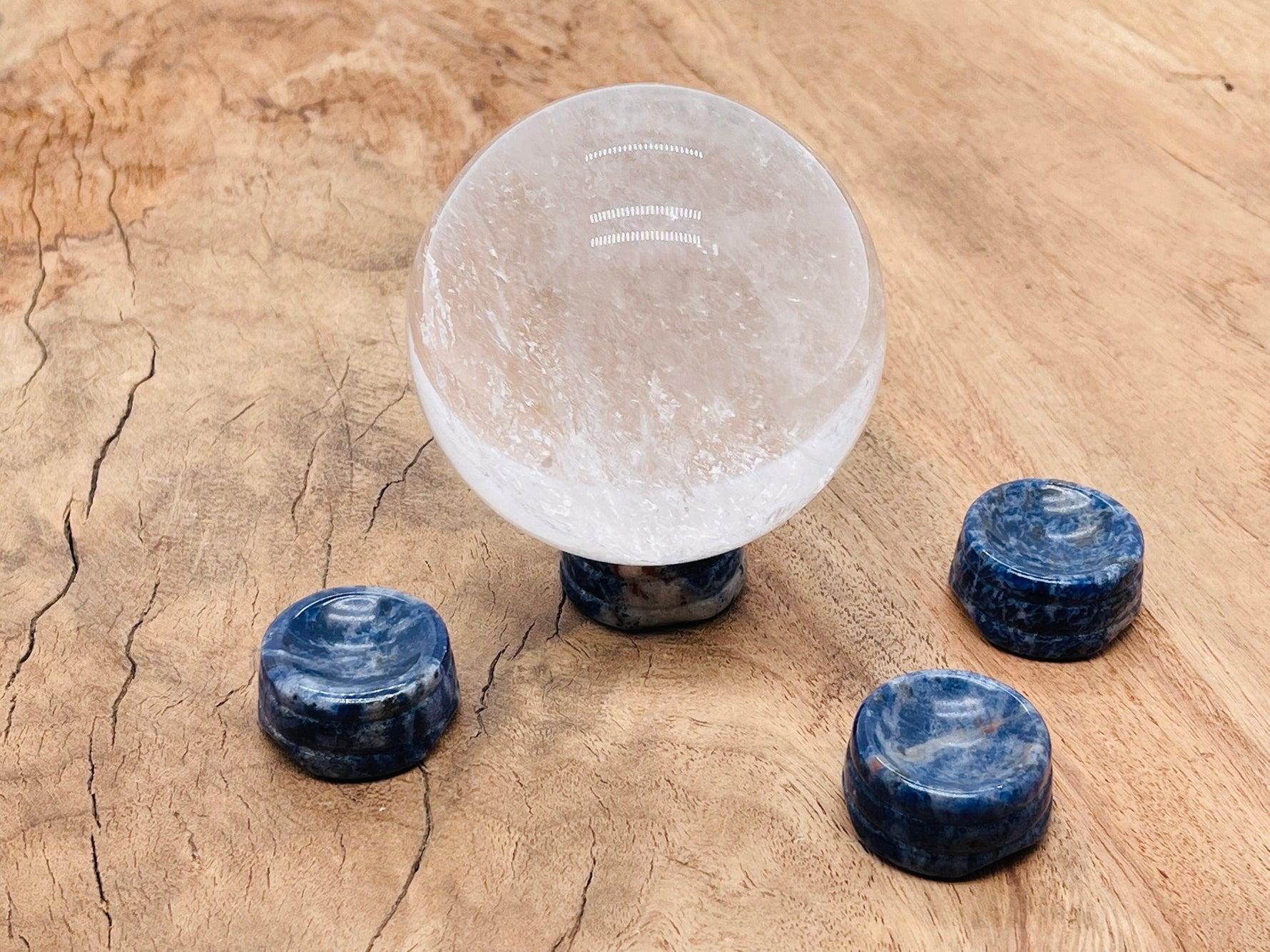 Sodalite crystal sphere on a carved gemstone stand, used as elegant home decor piece with blue and white natural stone patterns.
