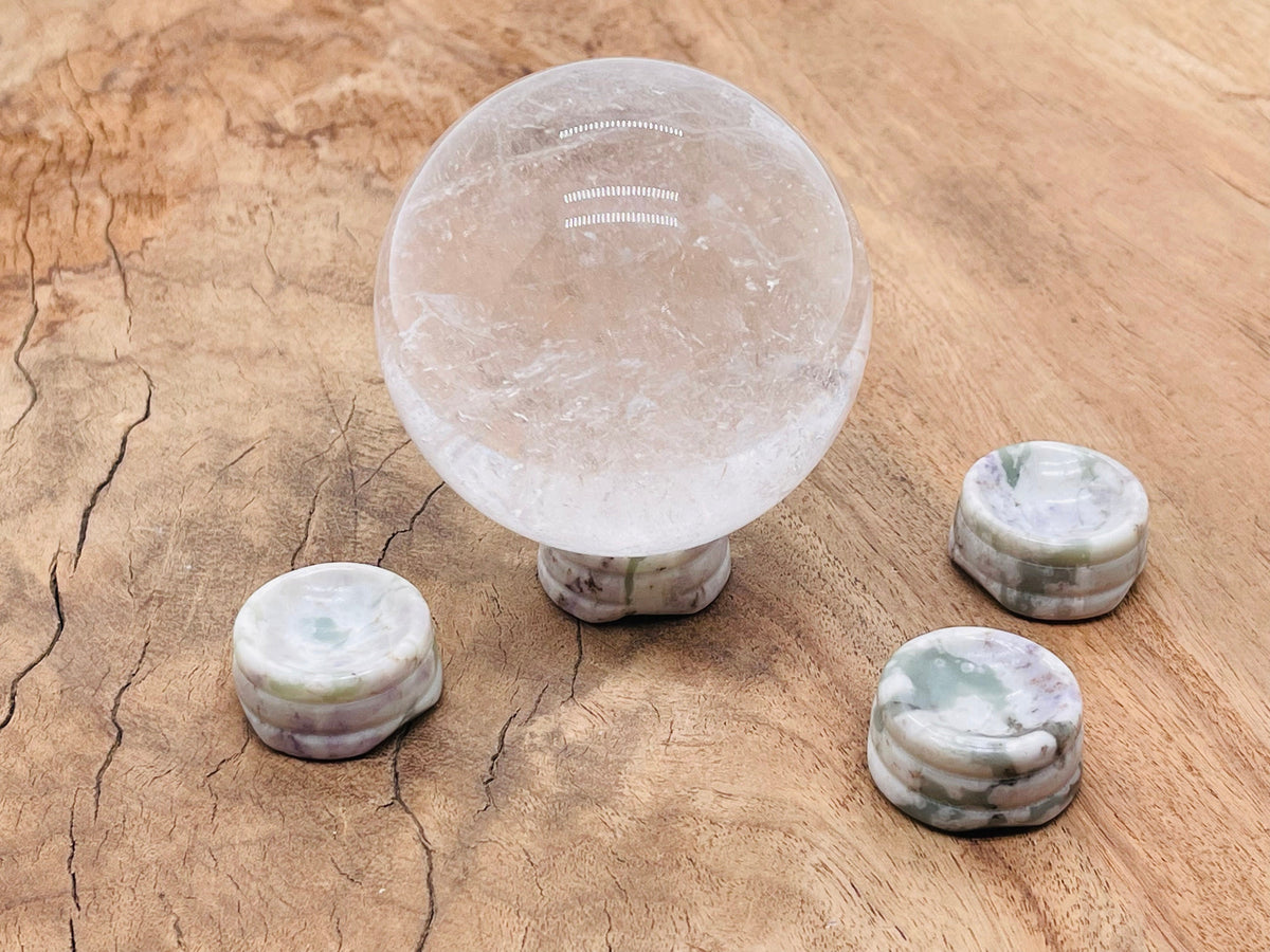 Peace Jade crystal sphere sitting on a carved gemstone stand, ideal for home decor and display.