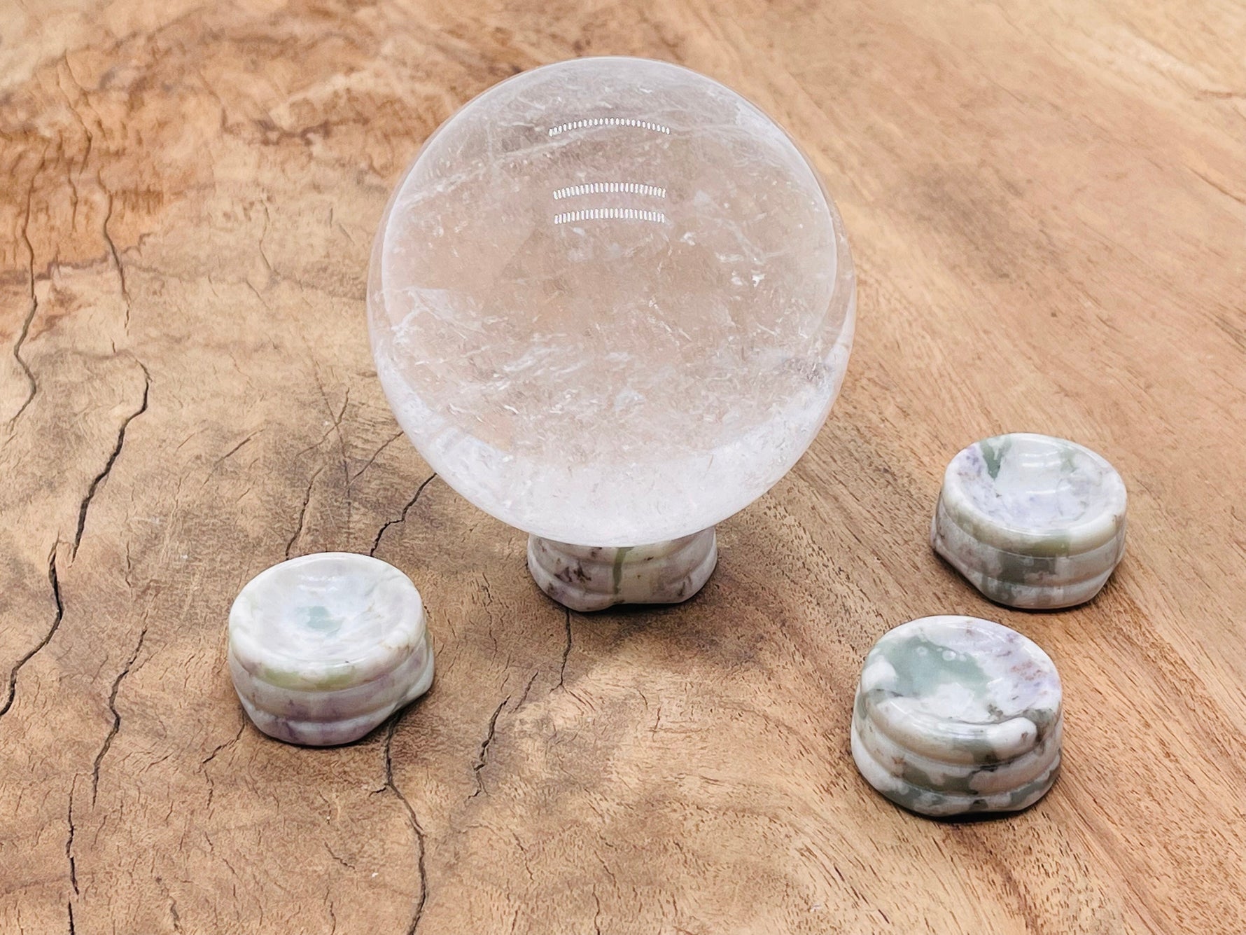 Peace Jade crystal sphere sitting on a carved gemstone stand, ideal for home decor and display.