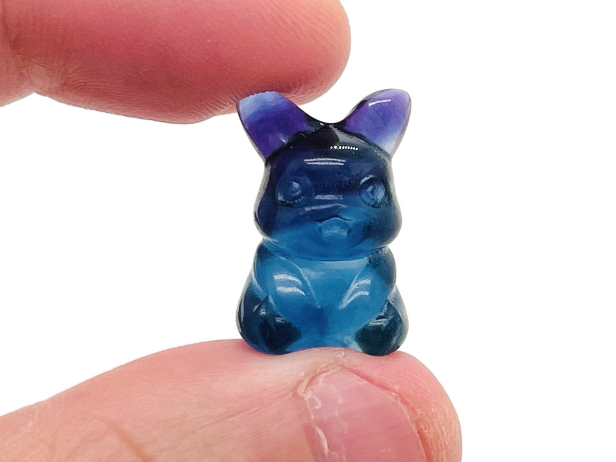 Colorful fluorite gemstone carved into a cute animal figure, showcasing vibrant hues and intricate detailing.