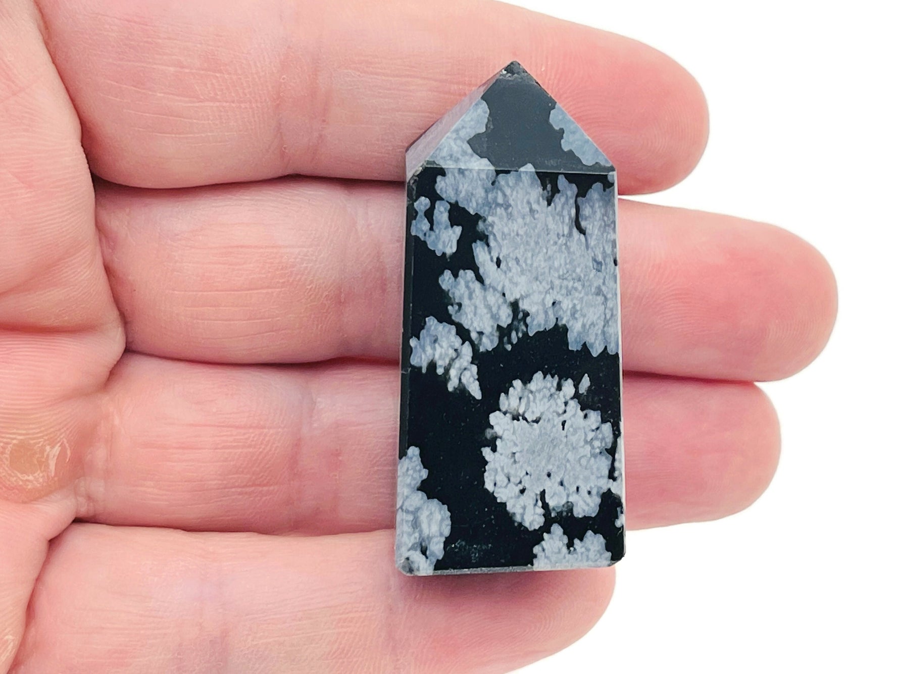 Snowflake Obsidian obelisk tower crystal from GemstoneGO, showcasing black stone with white snowflake patterns and a pointed shape.