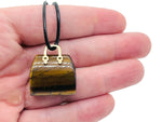 Tiger Eye crystal carving of a purse gemstone, handcrafted handbag pendant with detailed gemstone craftsmanship.