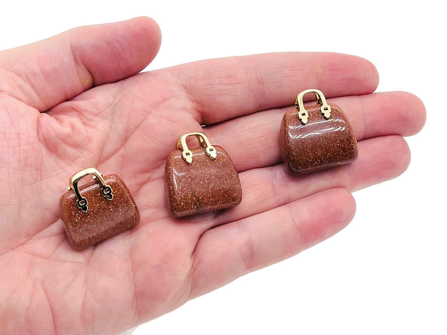 Goldstone crystal handbag pendant with intricate carving, featuring a sparkling, gold-toned gemstone for jewelry and accessory use.