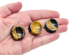 Tiger Eye crystal sphere resting on a carved gemstone stand, used as elegant home decor piece.