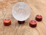 Red Jasper crystal sphere on carved gemstone stand, decorative home decor piece showcasing vibrant red mineral and smooth polished surface.