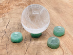 Aventurine crystal sphere on a carved gemstone stand, showcasing vibrant green hues, ideal for home decor display.
