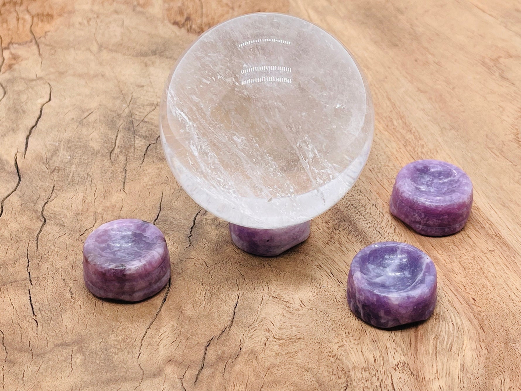 Lepidolite crystal sphere on carved gemstone stand, decorative home decor piece showcasing purple and lavender hues.