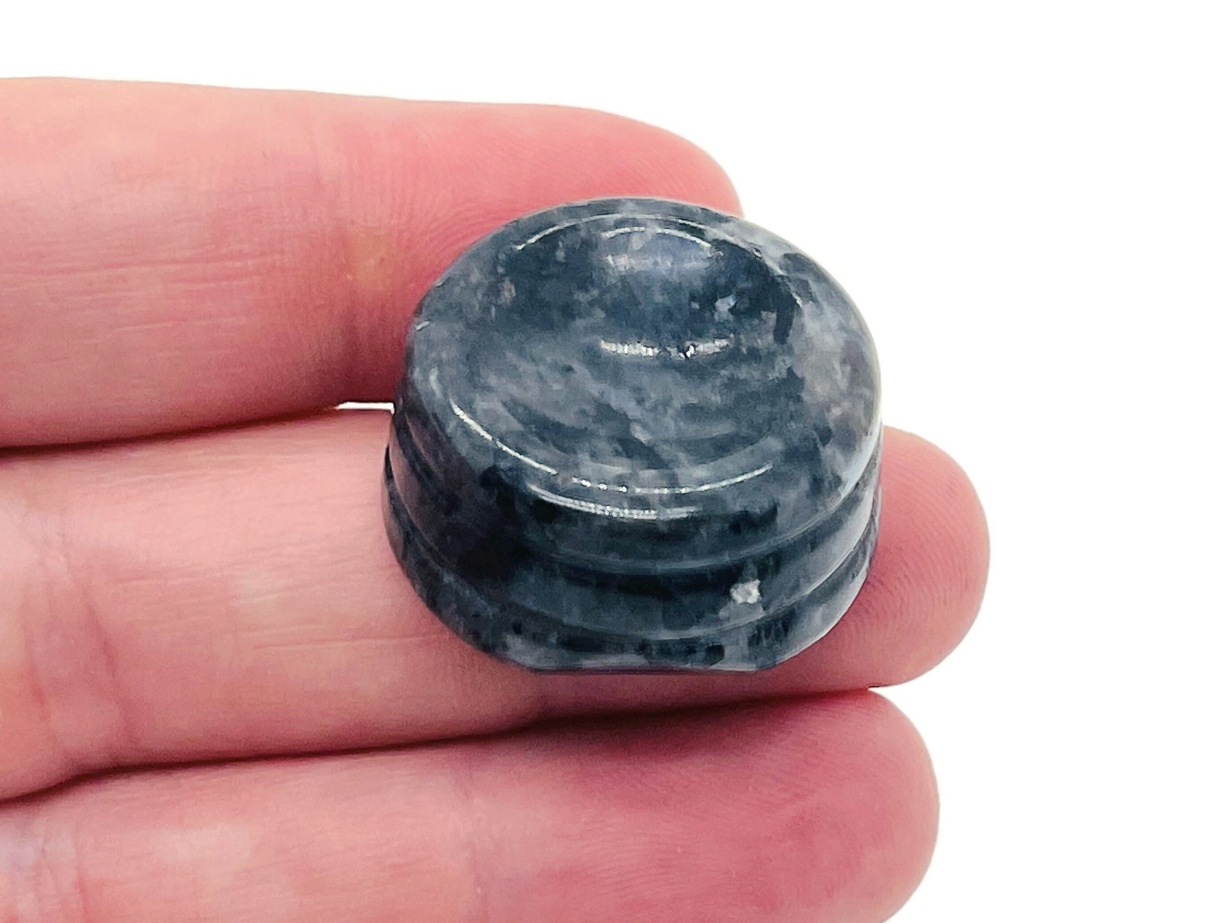 Larvikite crystal sphere on carved gemstone stand, used as elegant home decor piece showcasing natural gemstone beauty.