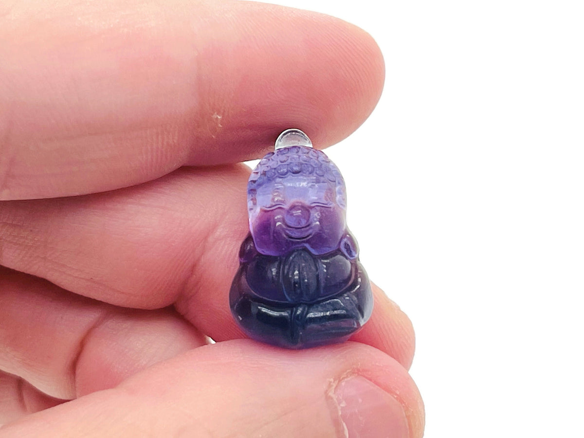 Fluorite Buddha carving gemstone from GemstoneGO, showing a detailed, polished Buddha figure in vibrant purple and green fluorite.
