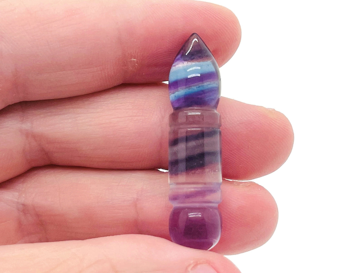 Fluorite bullet-shaped gemstone carving by GemstoneGO, showcasing vibrant purple and green colors with smooth polished surface.