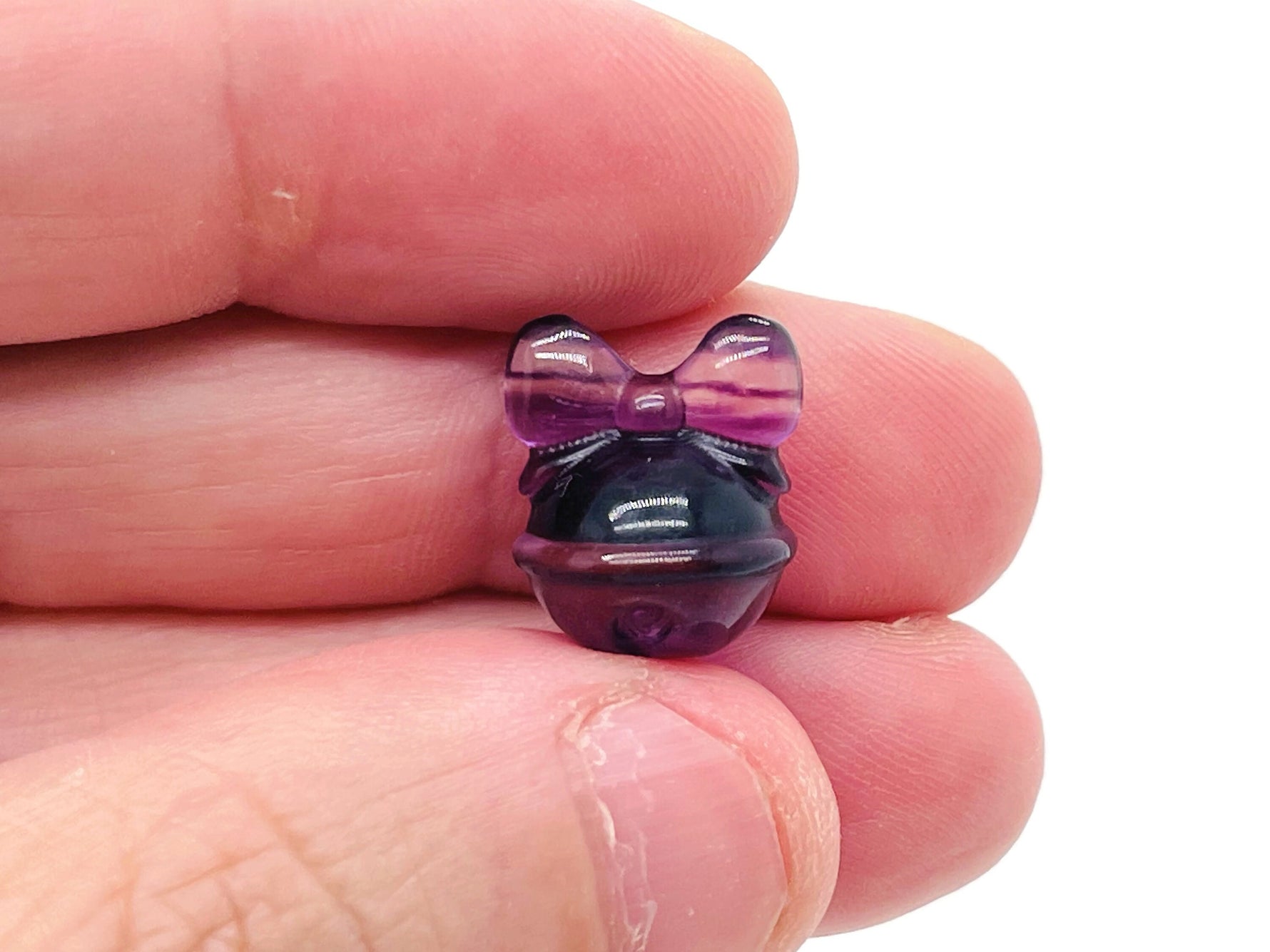 Polished fluorite crystal carving gemstone from GemstoneGO showcasing vibrant purple and green hues with intricate detailing.