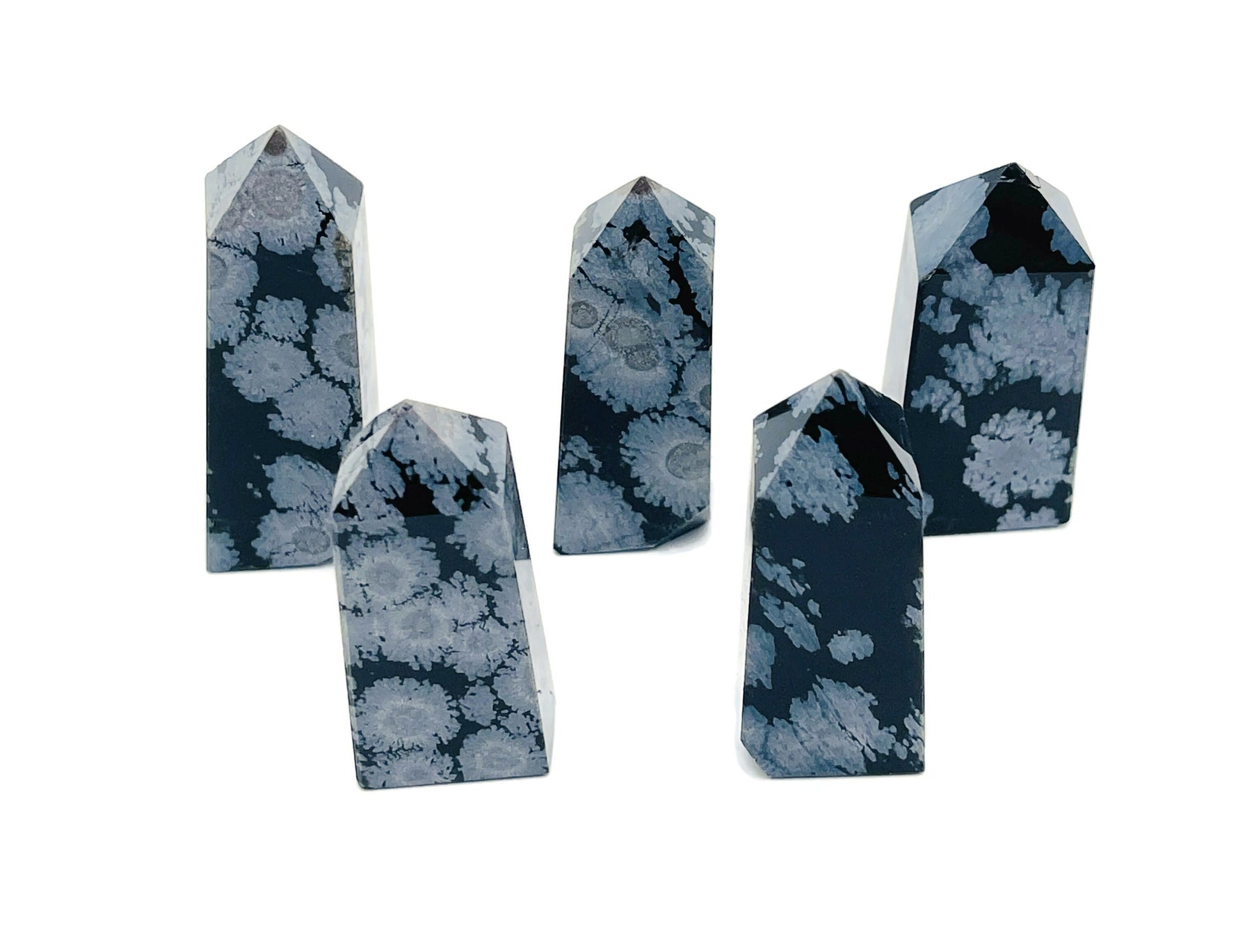Snowflake Obsidian obelisk tower crystal from GemstoneGO, showcasing black stone with white snowflake-like patterns.