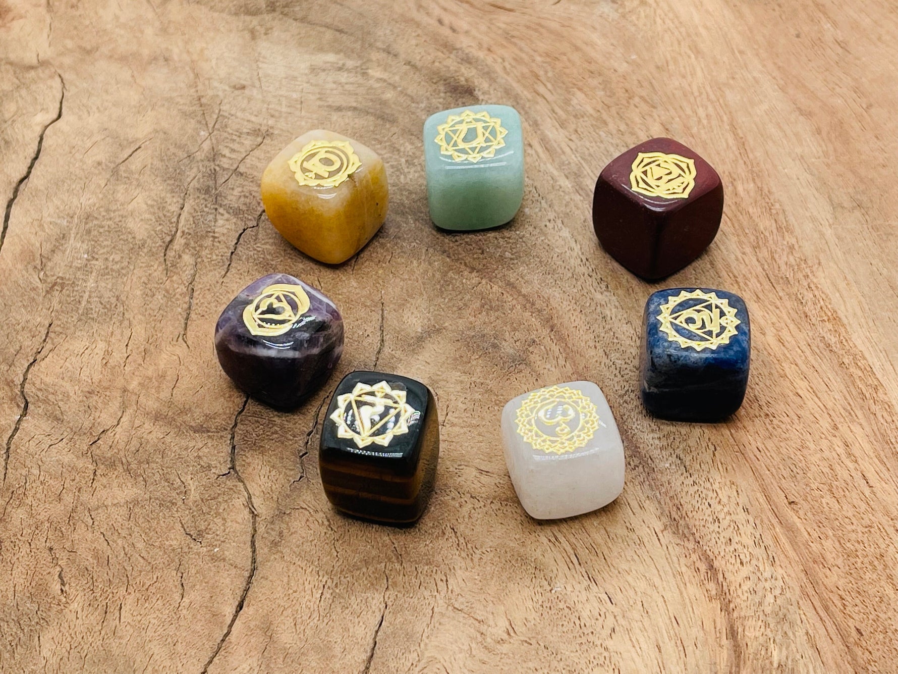 Set of seven natural chakra stones in various colors for meditation, arranged in a row with a calming background.