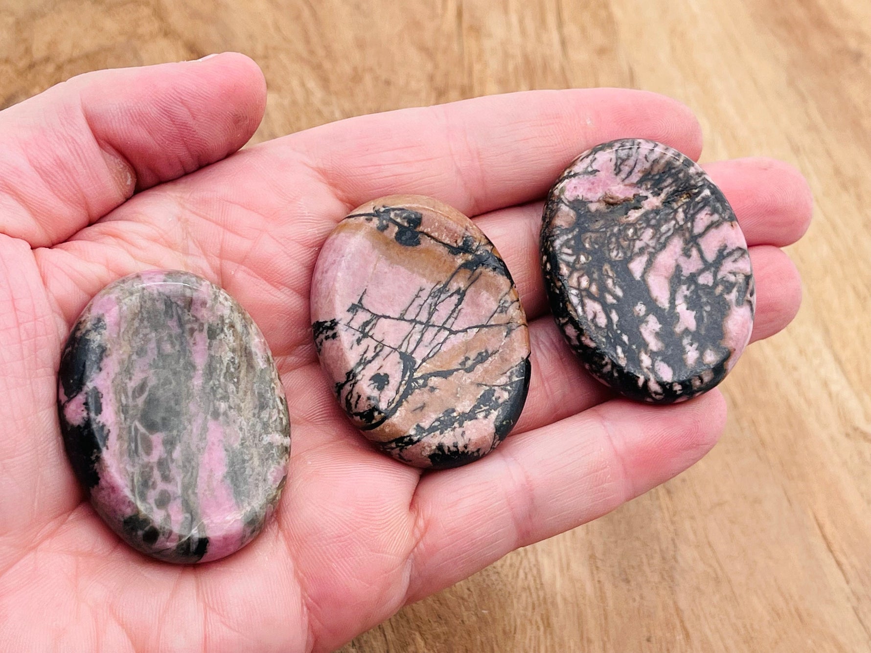 Rhodonite worry stone with soothing pink and black patterns, 4.5x3.5cm, polished gemstone for stress relief and meditation.