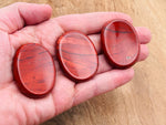 Red Jasper worry stone from GemstoneGO, a soothing 4.5x3.5cm crystal for stress relief, with polished, smooth surface.