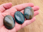 Moss Agate palm gemstone spa stone, 45x35mm, showing green and brown moss-like patterns on polished stone surface.