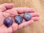 Lepidolite heart crystal pendant from GemstoneGO, showcasing a polished, purple gemstone with silver chain detail.