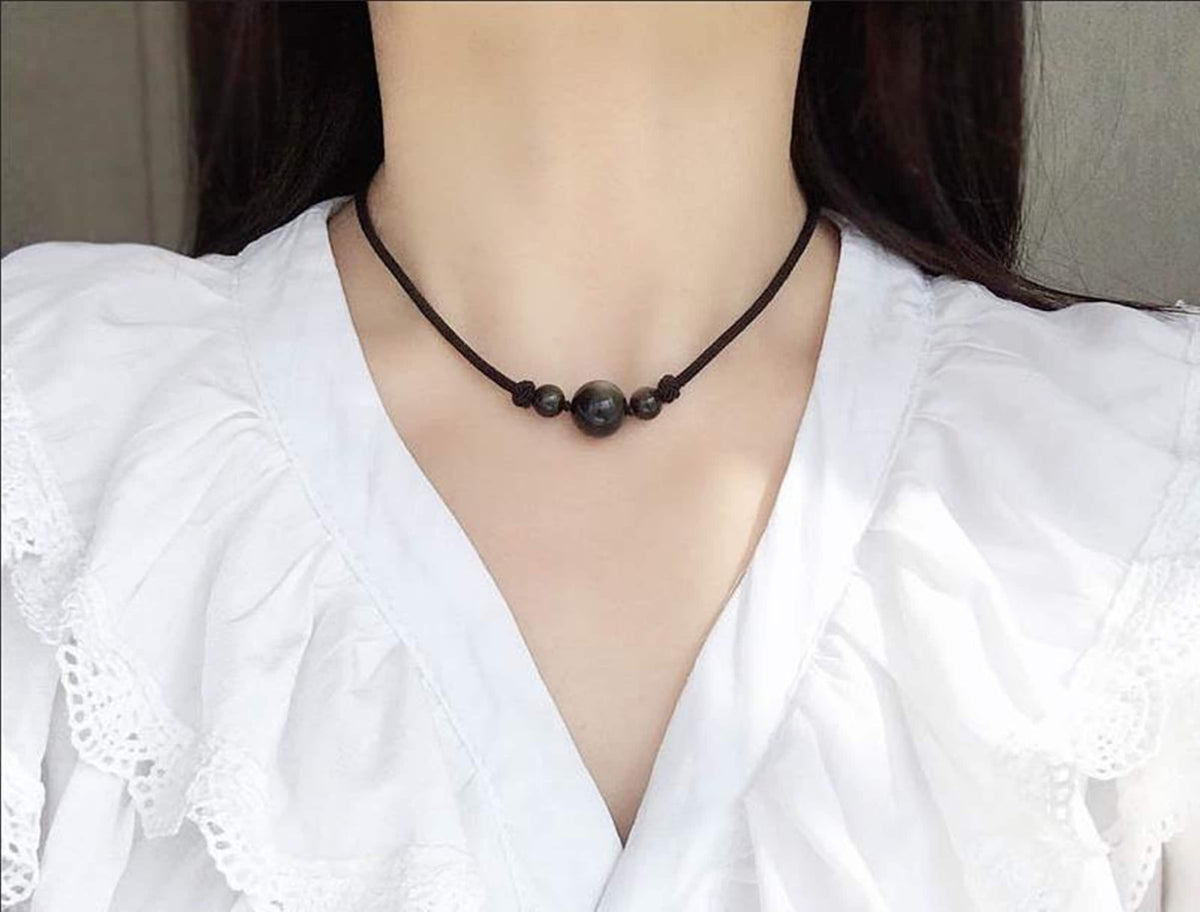 Obsidian sphere crystal pendant on a cord necklace, showing a glossy black gemstone with natural texture and smooth rounded shape.