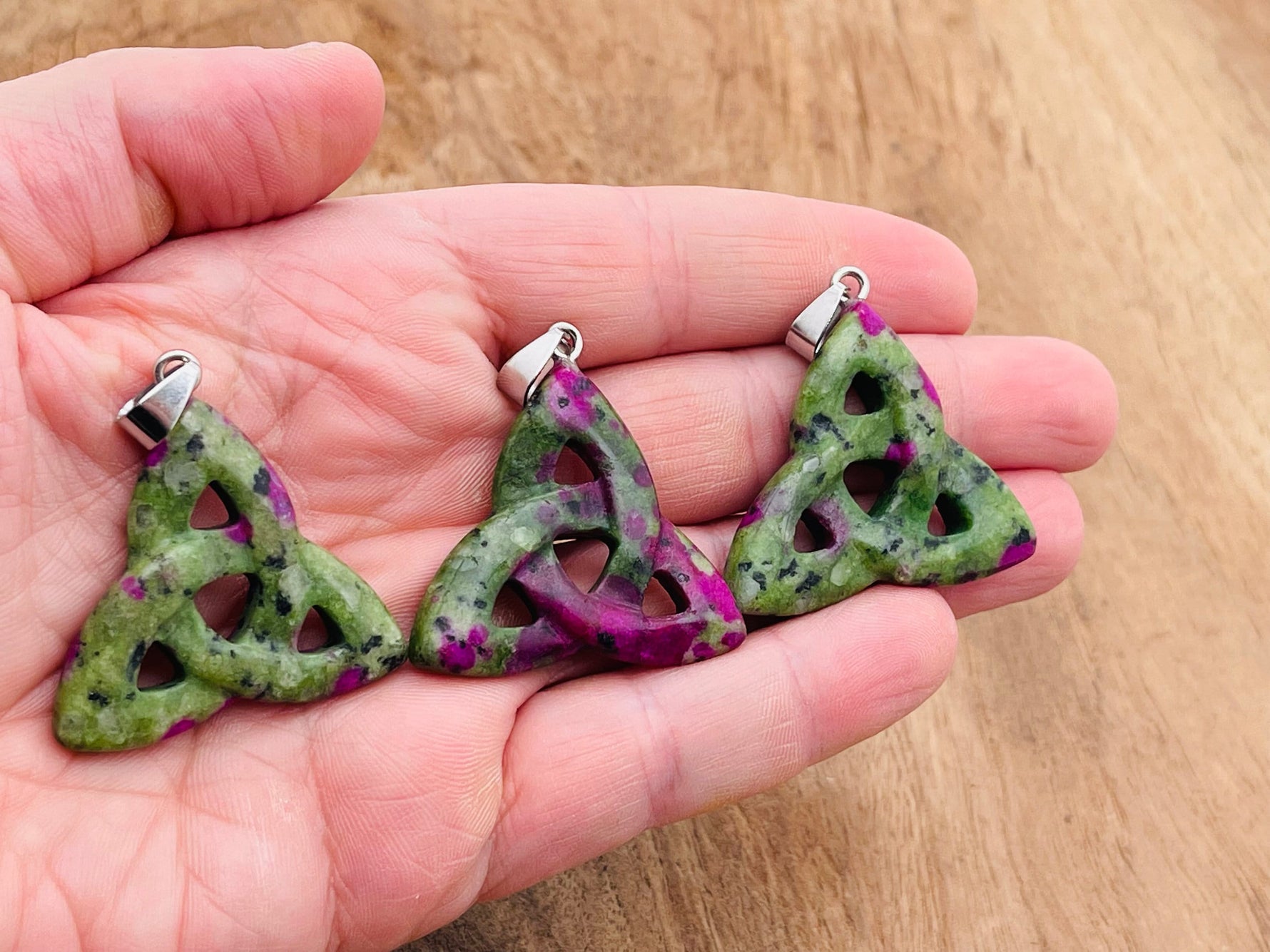 Ruby Zoisite Celtic Knot crystal pendant featuring intricate Trinity Crystals design, showcasing vibrant red and green gemstone details.