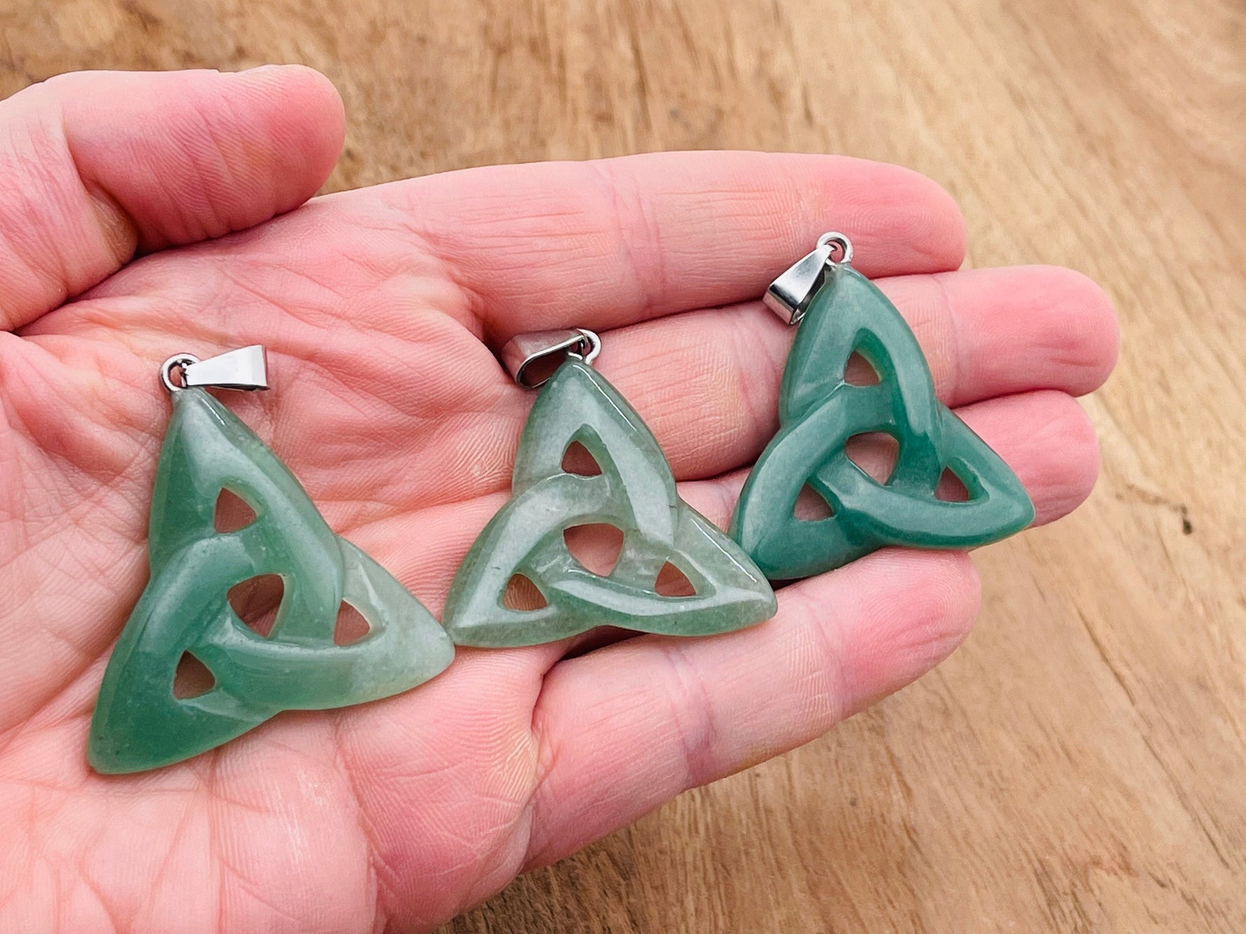 A aventurine Celtic knot crystal pendant with Trinity Crystals, featuring intricate green gemstone design on a silver chain.